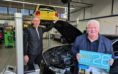 Fritz Faupel und Kai Bremmer stehen mit einem Auto und Prüfgerät in der Kfz-Werkstatt beim Licht-Sicht-Test.